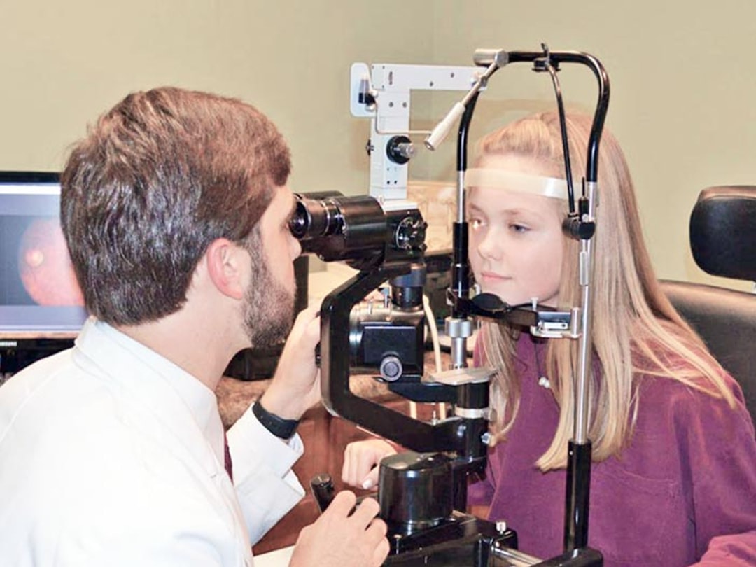 An optometrist examining a child's vision with clinical equipment
