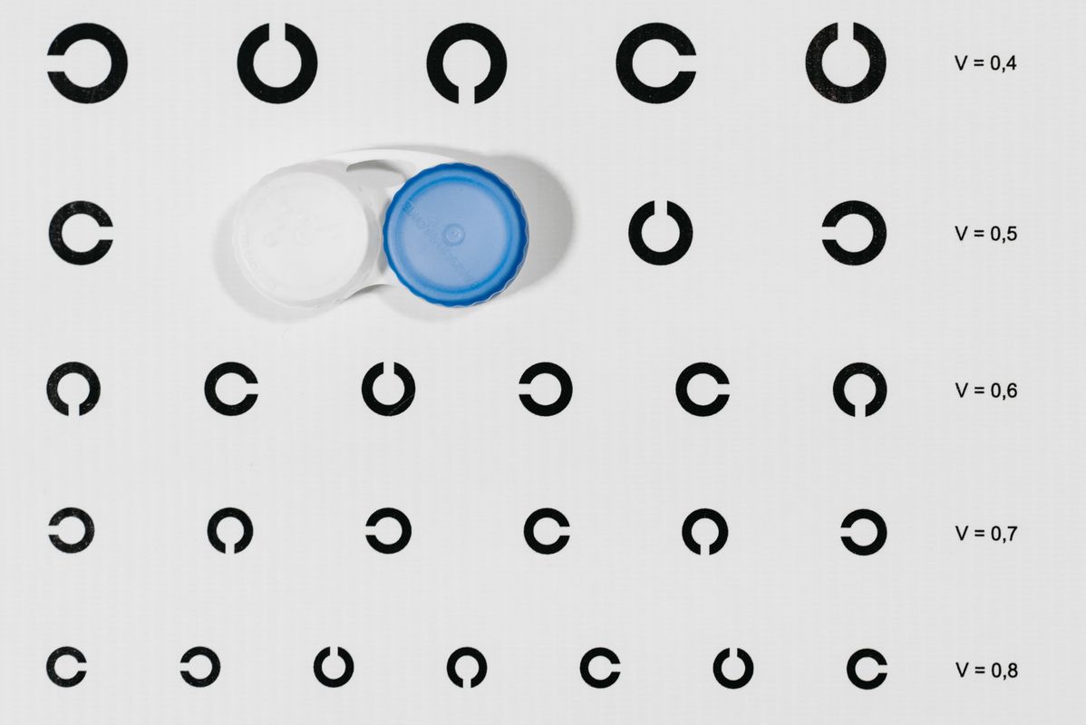 Contact lens case beside an eye chart, representing OrthoK overnight lens fitting