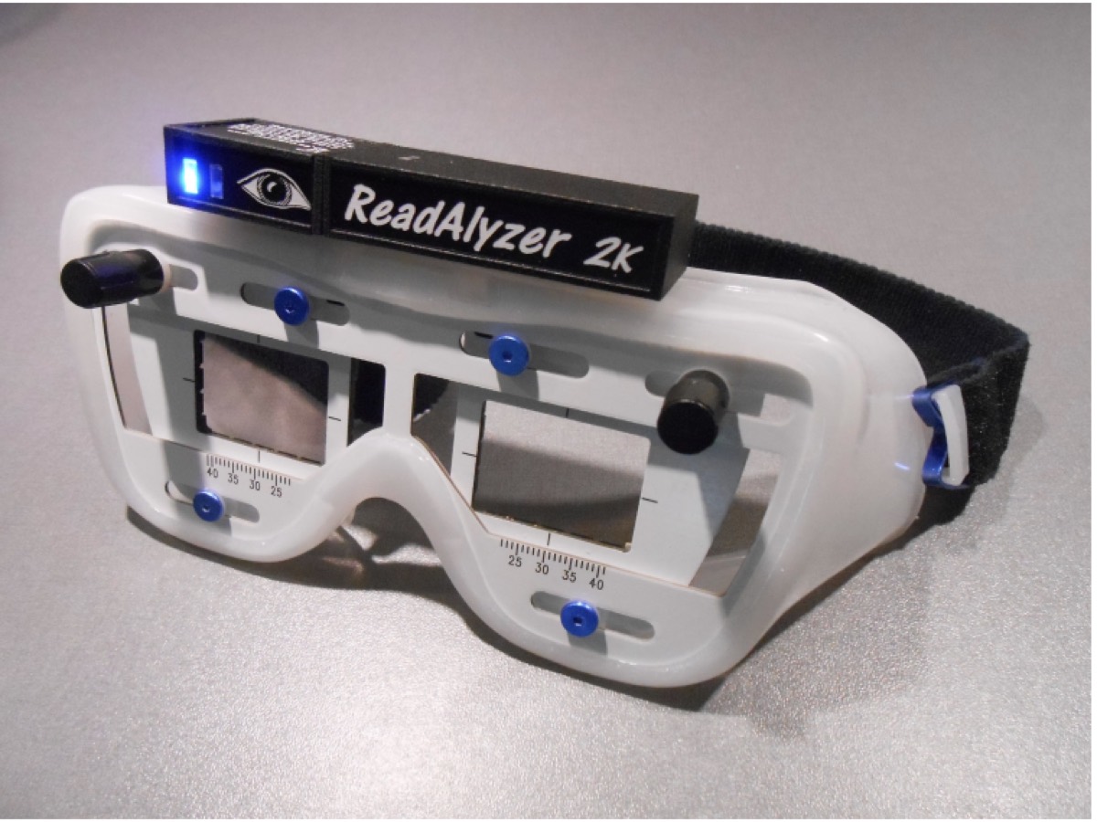 The ReadAlyzer 2K eye movement recording system — a pair of white goggles with a camera module built into the headband